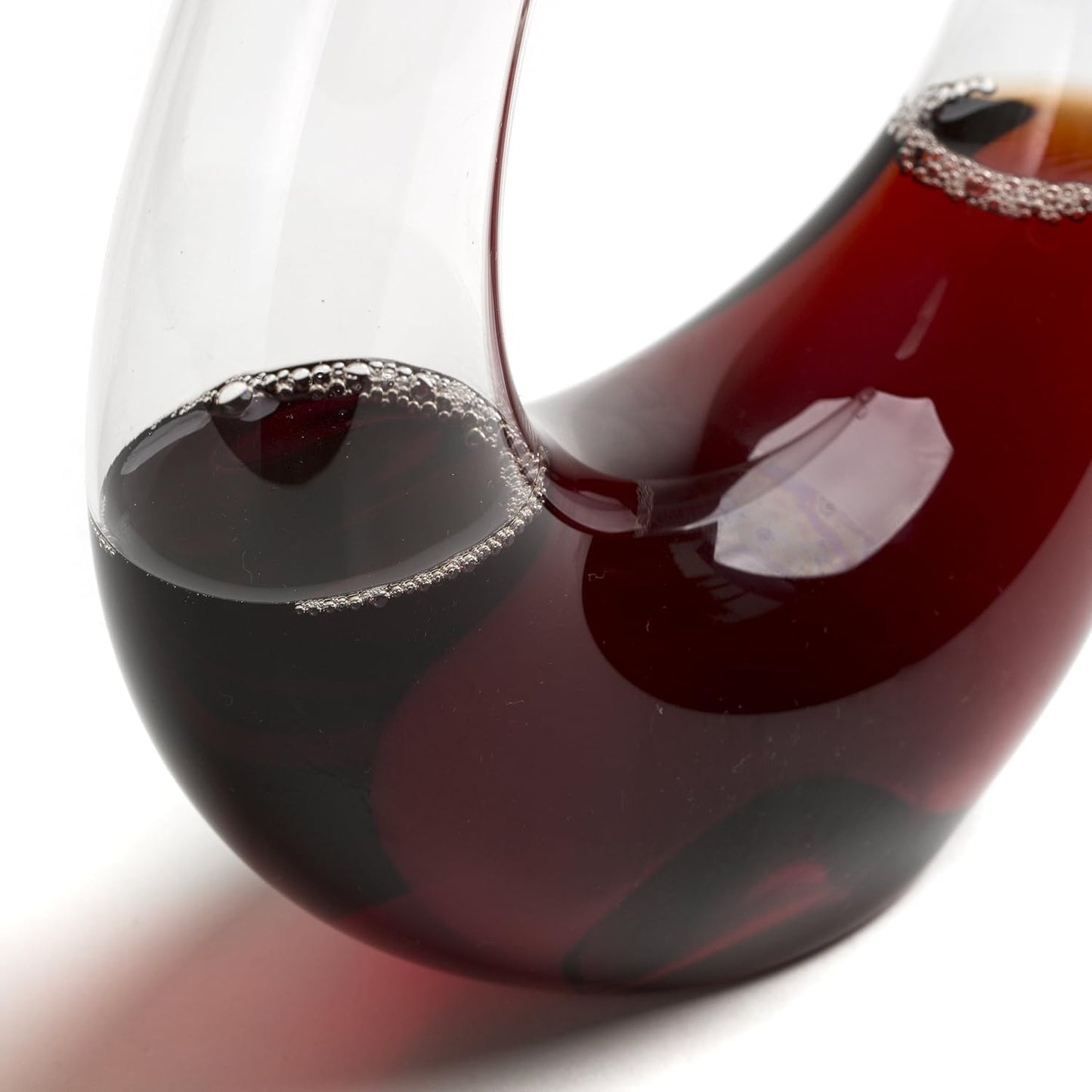 Close-up of curved glass aerator and dark red wine at the base