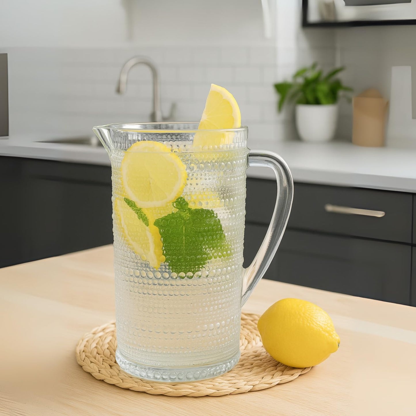 Clear hobnail glass pitcher with green-and-yellow decorative design, arched handle and spout.