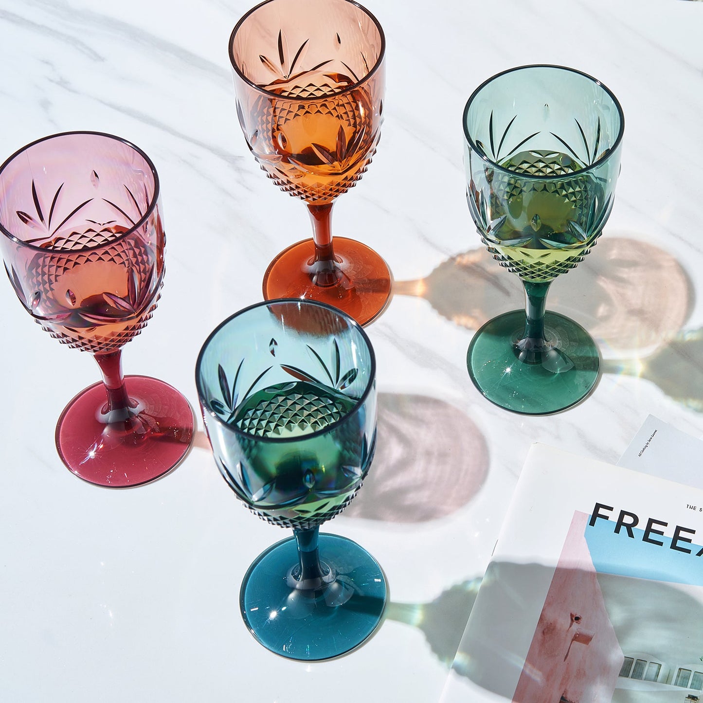 Stemmed wine glasses, faceted leaf/diamond cuts in orange, pink, green, teal-blue