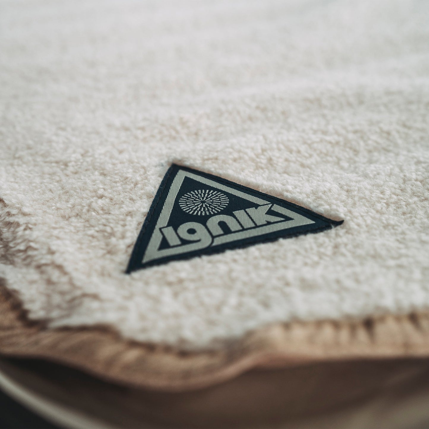 Close-up of triangular iGNiK logo on light fleece heated bed cover fabric