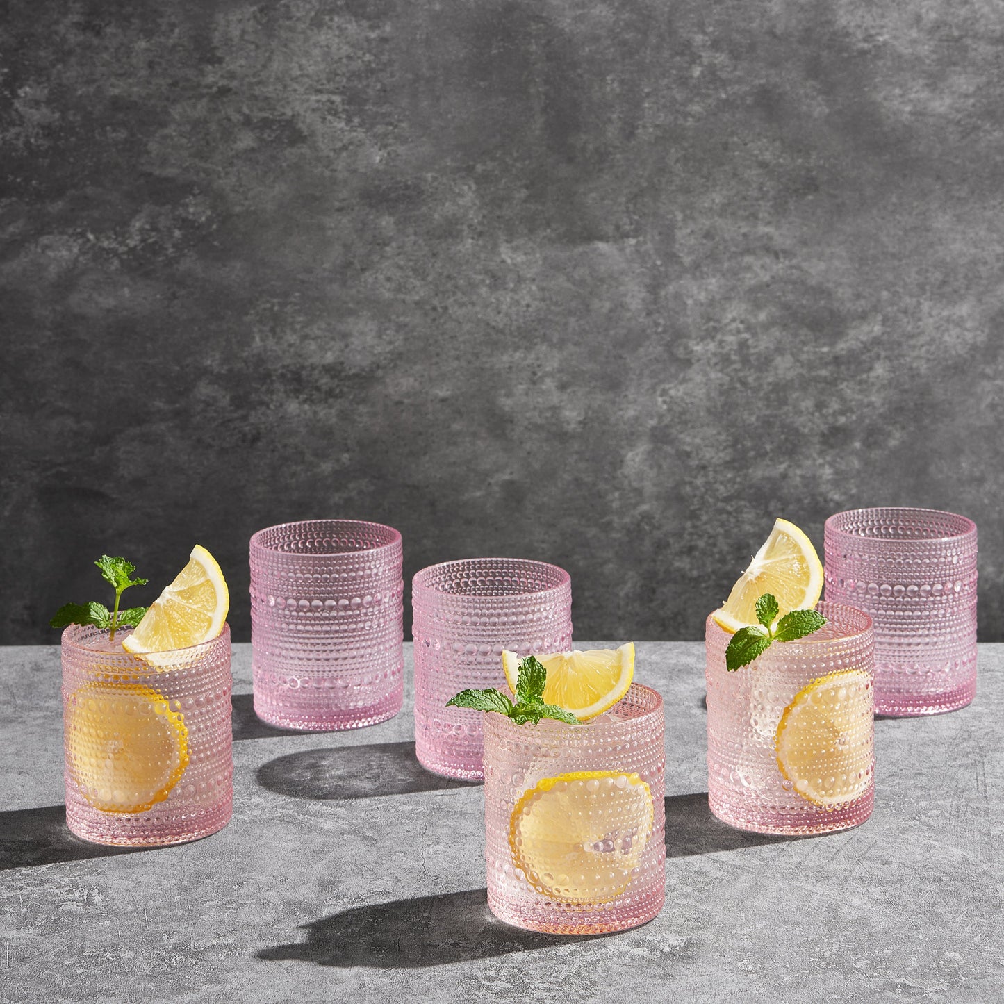 Pink hobnail lowball glasses with lemon slices, set of 6, on countertop