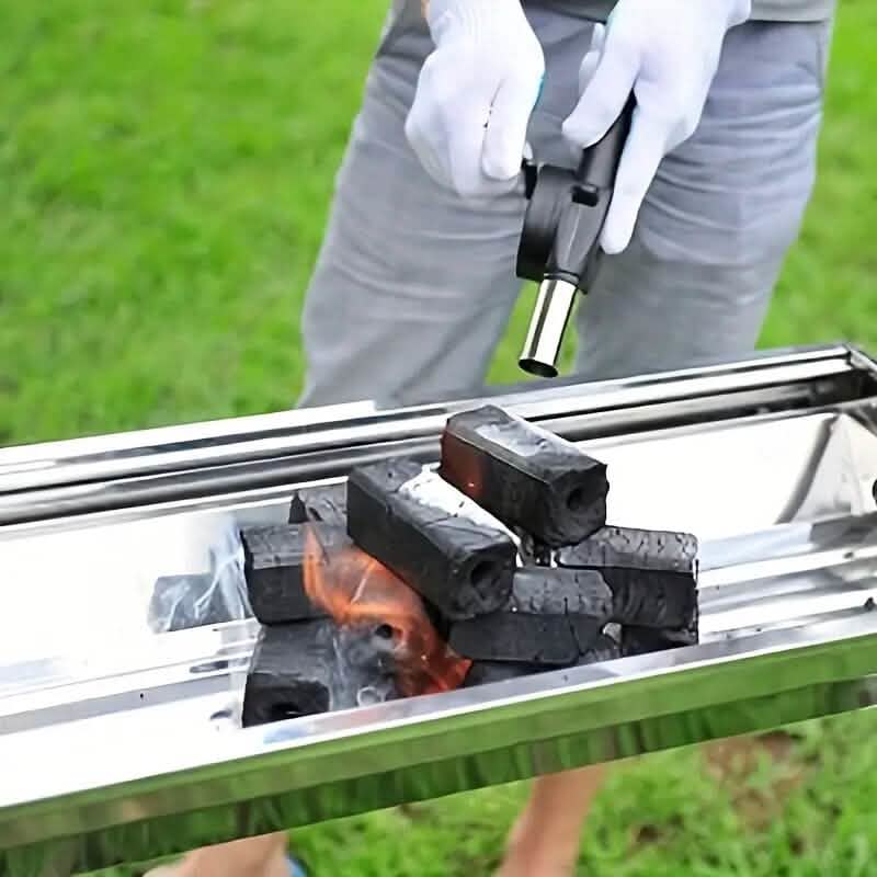 Fire blower nozzle directing airflow into charcoal in a grill tray