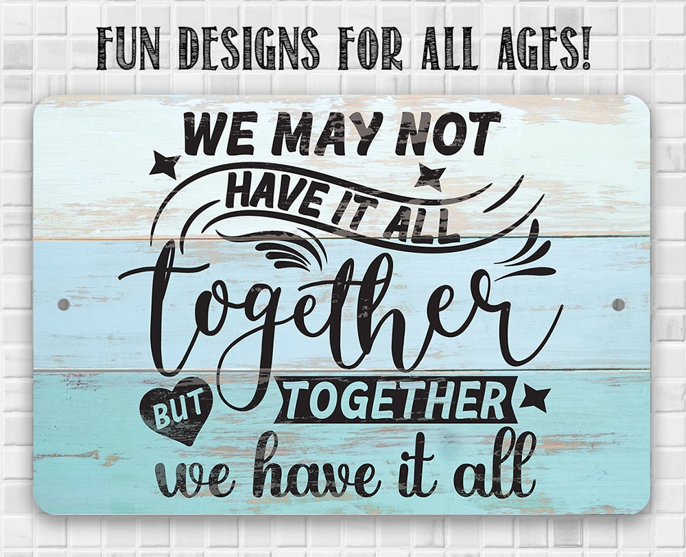 Metal sign with blue wood-look and black script “We may not have it all… together we have it all”