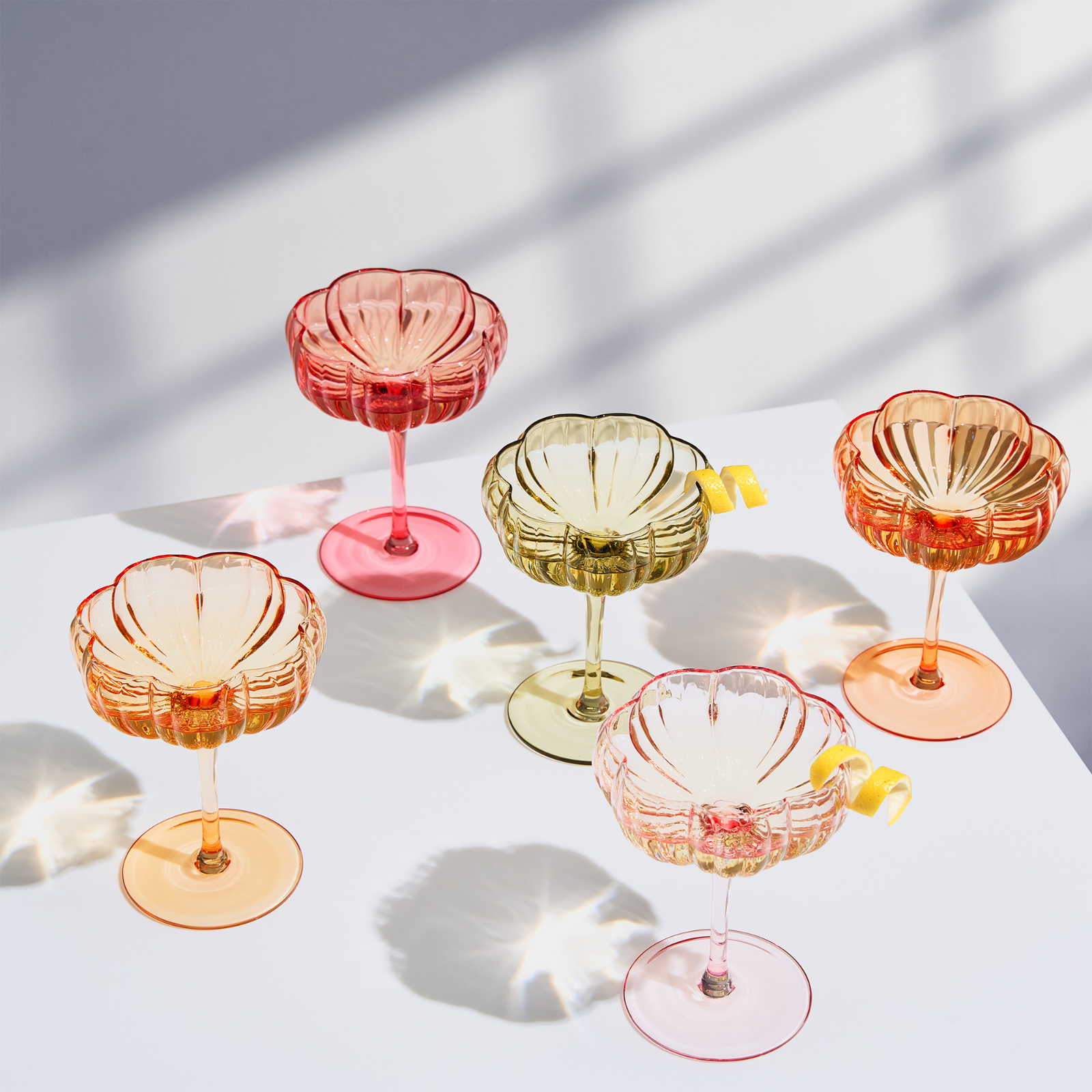 Set of 4 flower-shaped coupe cocktail glasses, pink, gold, and orange tones with wavy rim