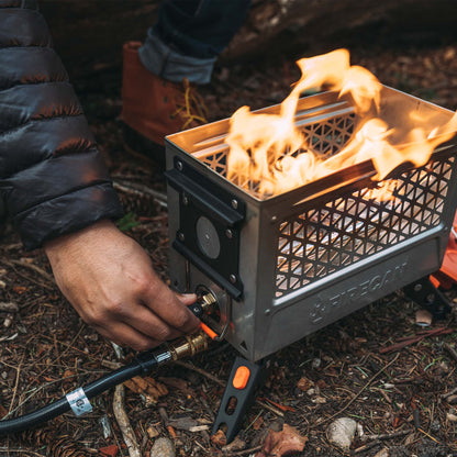 FireCan Elite fire pit lit with flames, vented steel grate and orange control knob