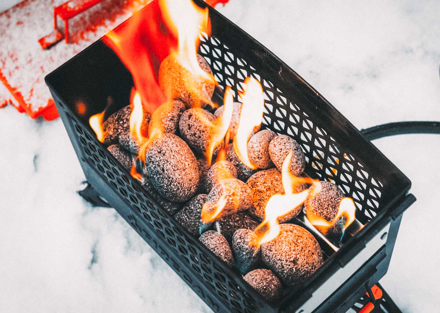 FireCan rocks in black fire pit basket with flames and glowing stones
