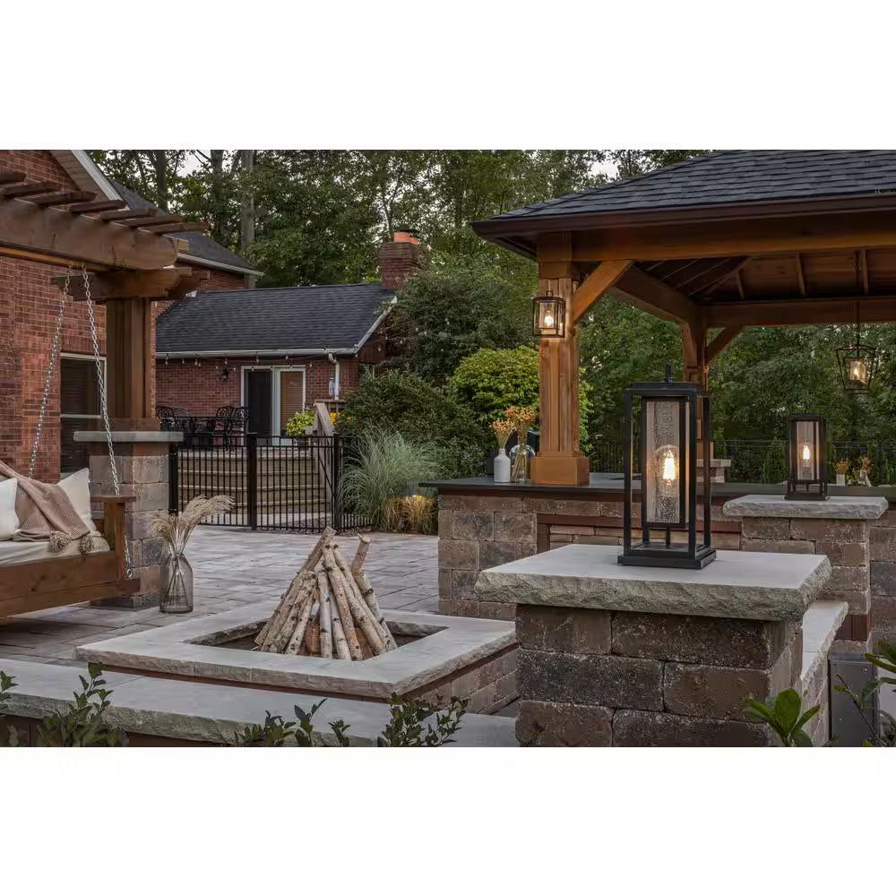 Black outdoor lanterns with clear glass panels and warm light on patio wall