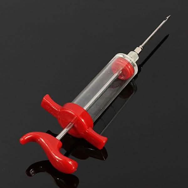 Marinade injector syringe with clear barrel and red clamp, angled metal needle