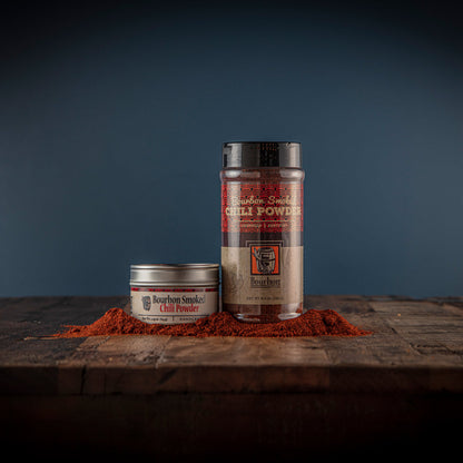 Bourbon smoked chili powder jars with red chili powder on wooden board