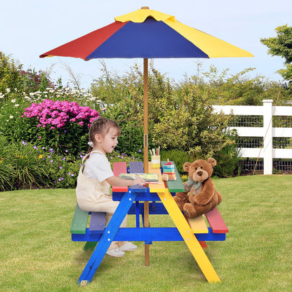 Kids picnic table with multicolor umbrella, child seated and teddy near tabletop