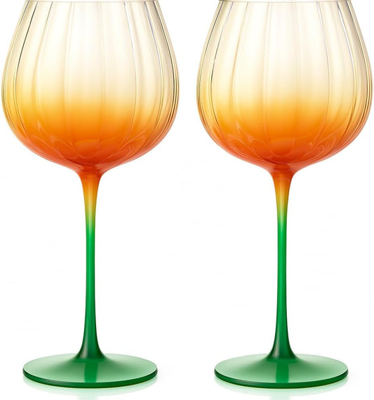 Set of 2 pumpkin-shaped wine glasses with orange liquid, clear cups, green stems