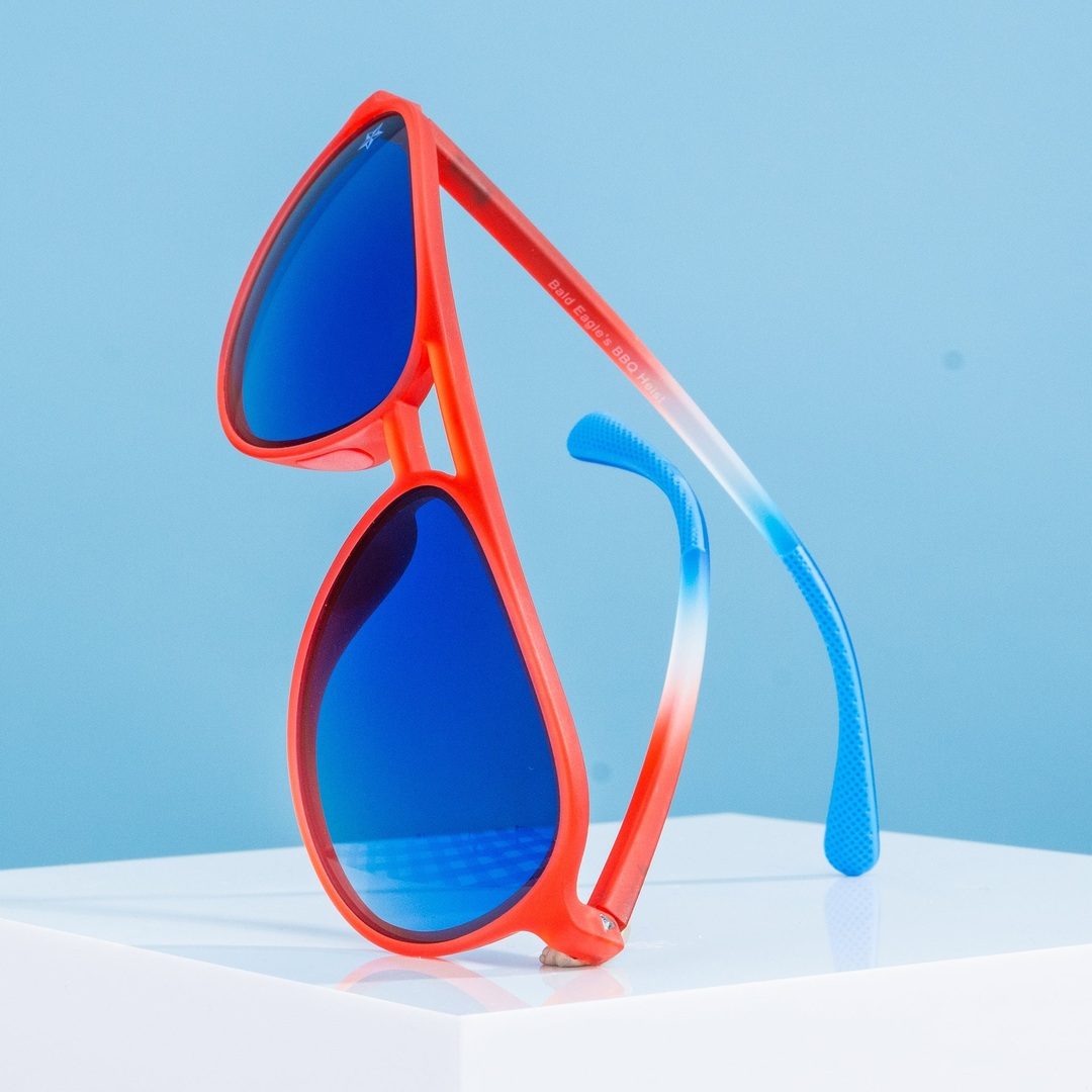Red aviator sunglasses with blue mirrored lenses, angled side view of temples.