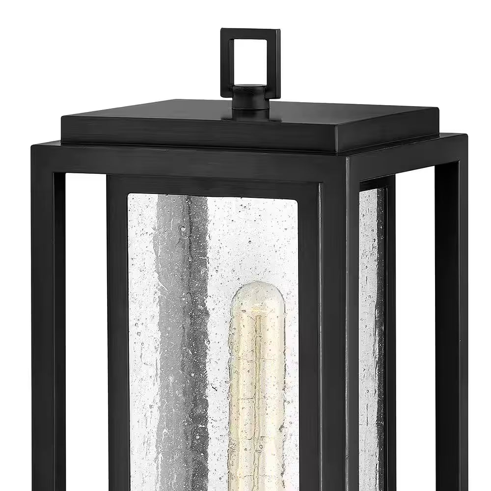 Black outdoor wall lantern top view with clear glass sides and glowing bulb