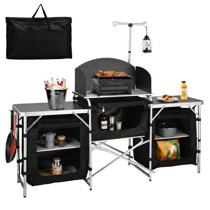 Folding camping kitchen station with grill and side shelves, plus black carry storage bag
