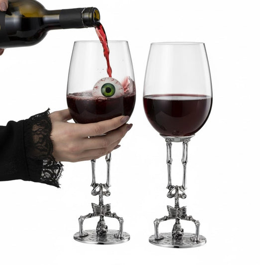 Pair of skeleton gothic wine glasses with skull bases and silver stems, filled dark red