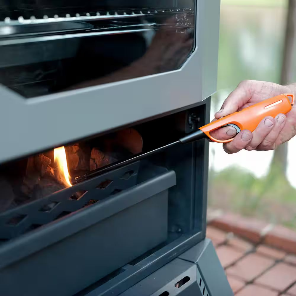 Digital charcoal smoker with open firebox and hand lighting the coals