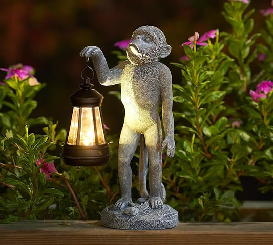 Gray monkey garden statue figurine holding a lantern with warm light, on a stone base