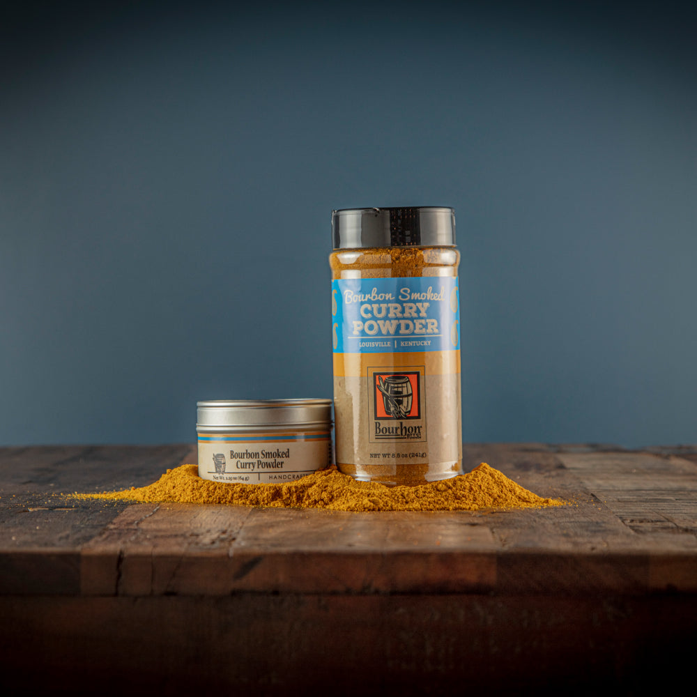 Bourbon smoked curry powder containers with a pile of gold-brown seasoning