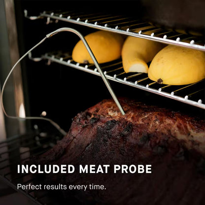 Smoker cooking chamber with meat probe in seasoned meat on wire racks