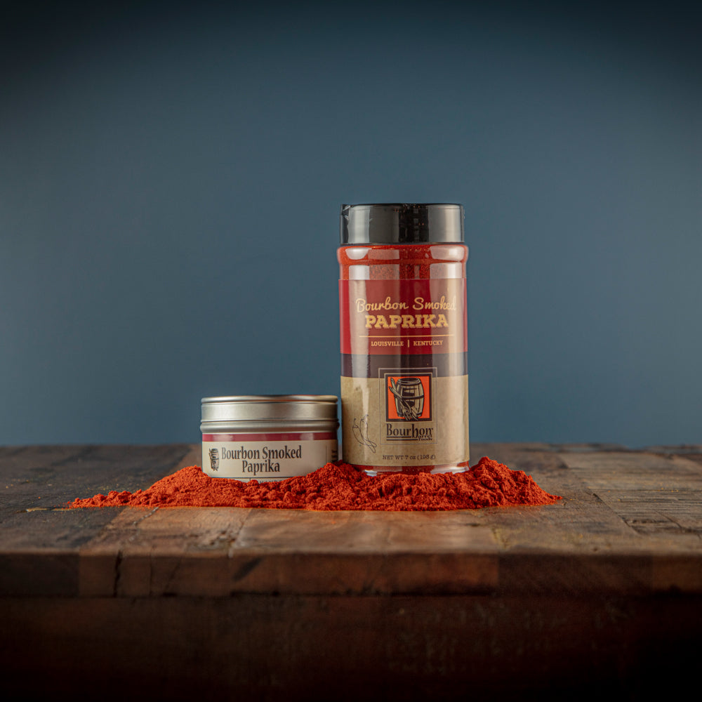 Smoked paprika spice jars with red ground seasoning on wooden board