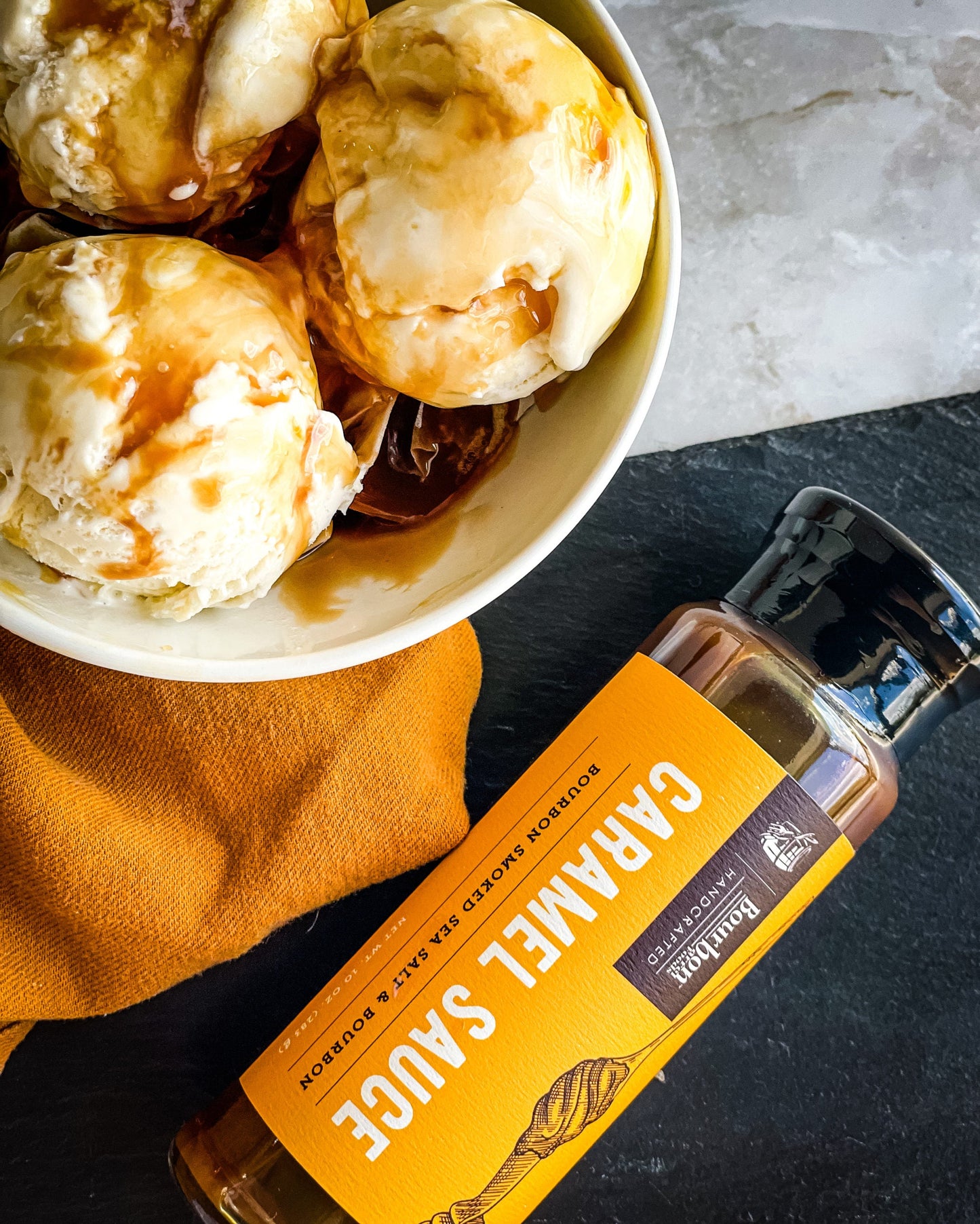 Caramel sauce bottle angled near a bowl of caramel-coated biscuits