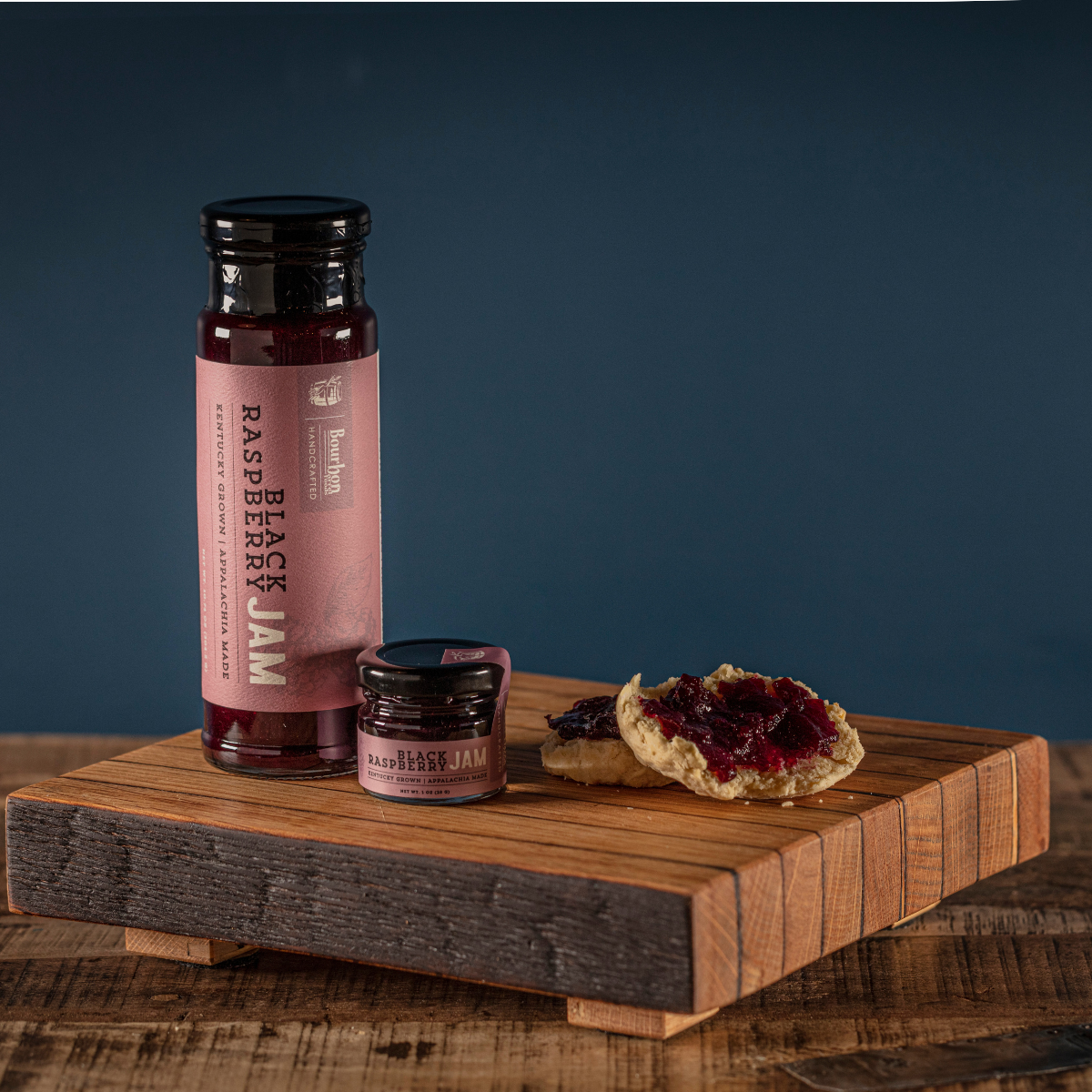 Black raspberry jam bottle and jar beside toast topped with jam