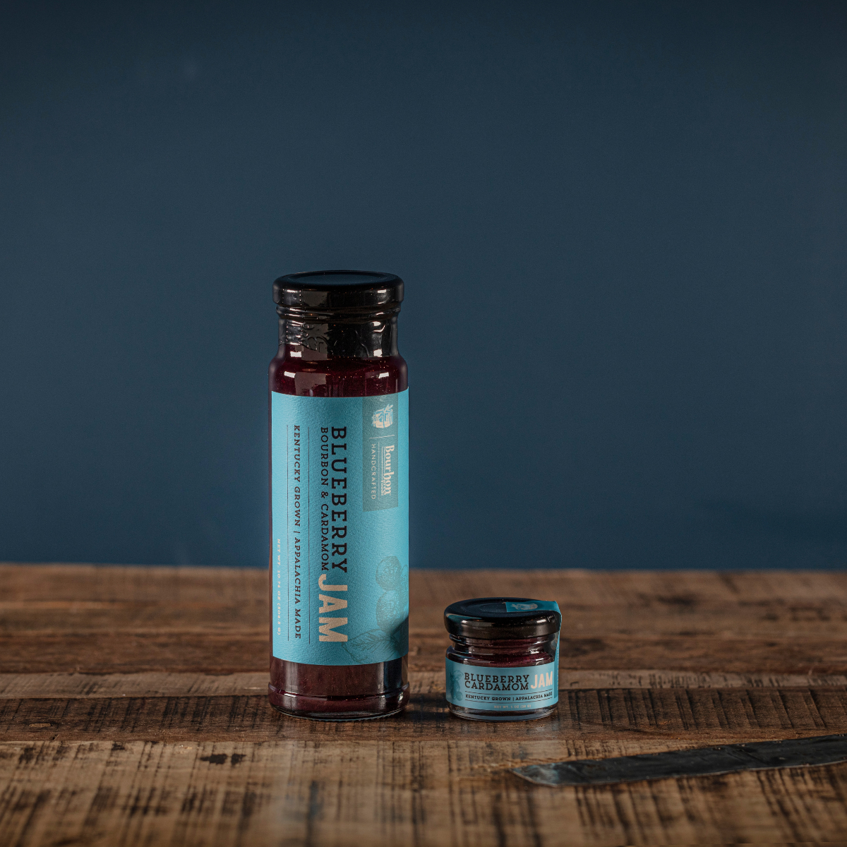 Blueberry cardamom jam jar and small jar with black lids, dark purple filling.