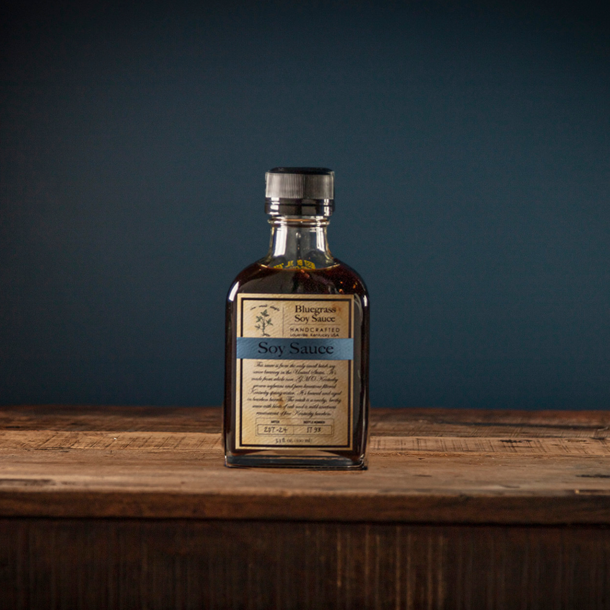 Soy sauce bottle, dark brown liquid, cream label with blue band, metal cap
