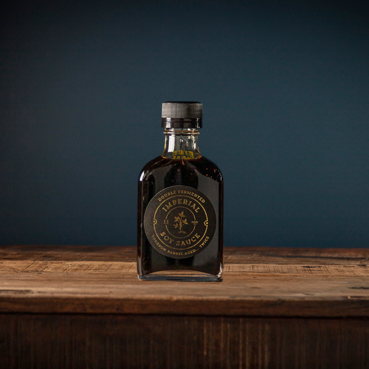 Soy sauce bottle with dark liquid and ribbed metal cap on wooden board