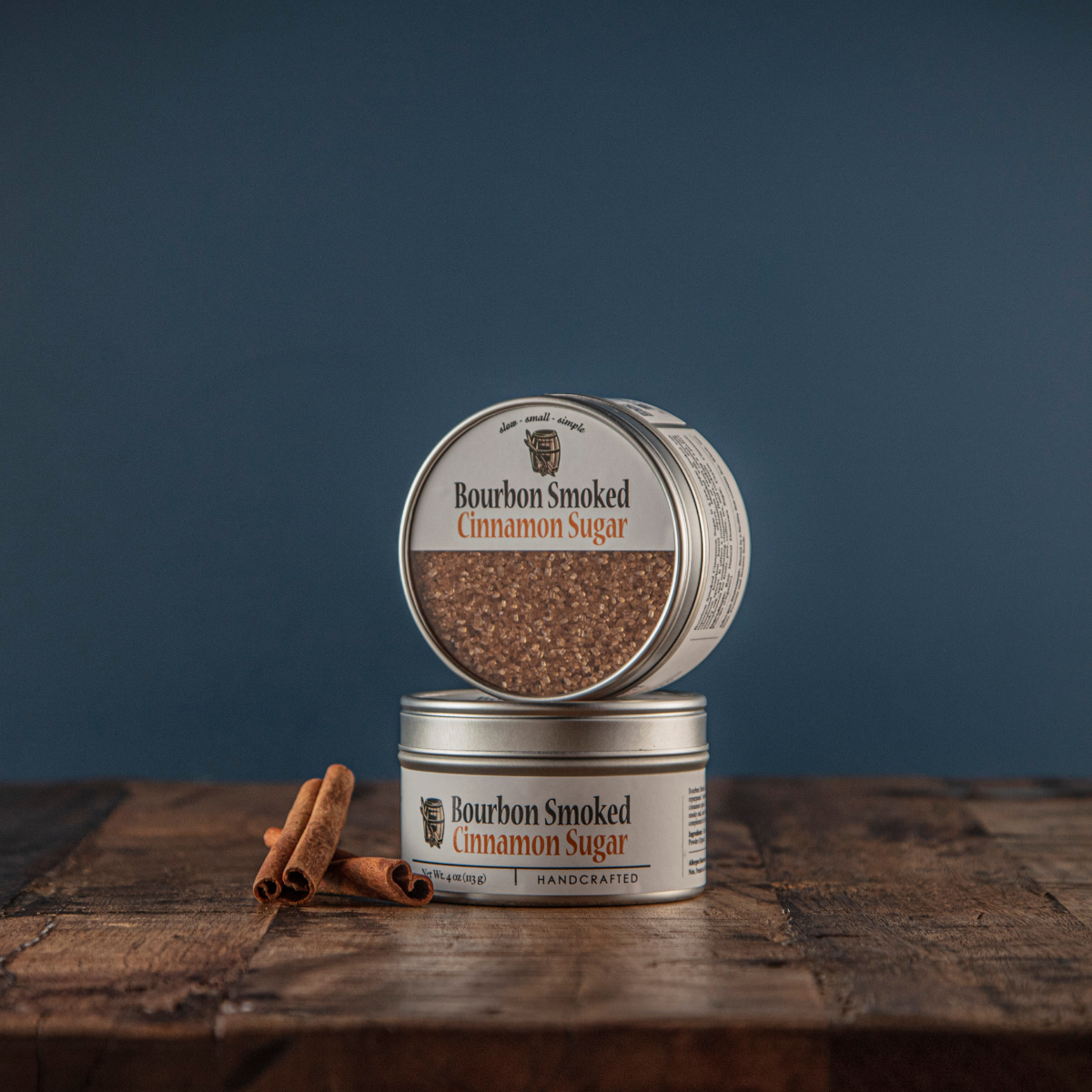 Bourbon smoked cinnamon sugar open tin with closed tin on wood, brown granules