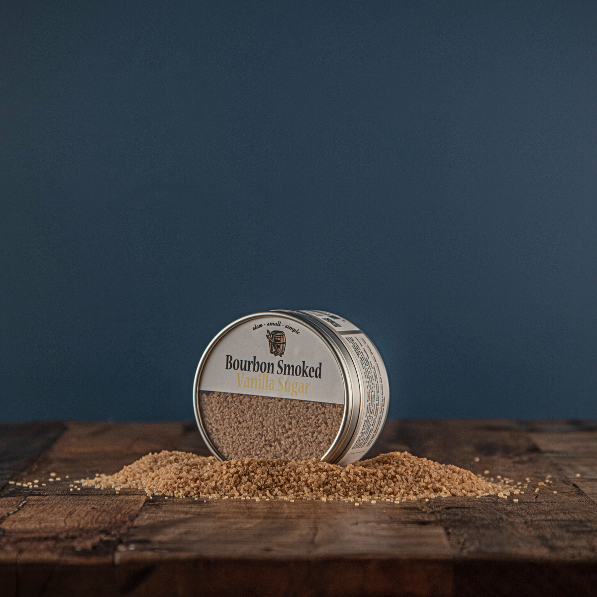 Smoked vanilla sugar tin with loose sugar granules scattered around it