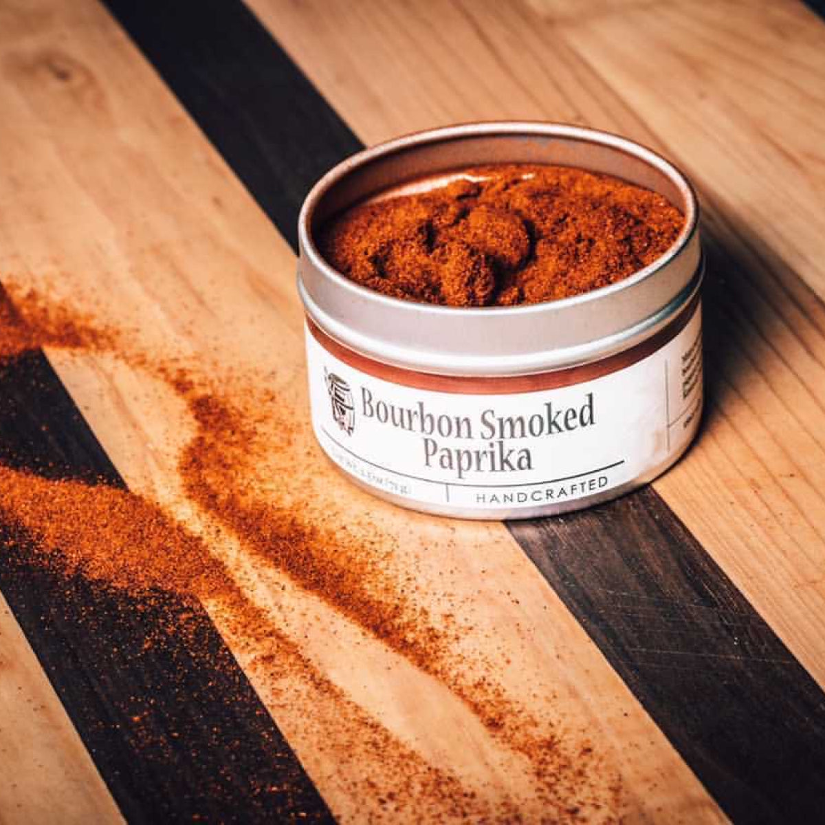 Smoked paprika spice jar lid filled with red ground seasoning on wood