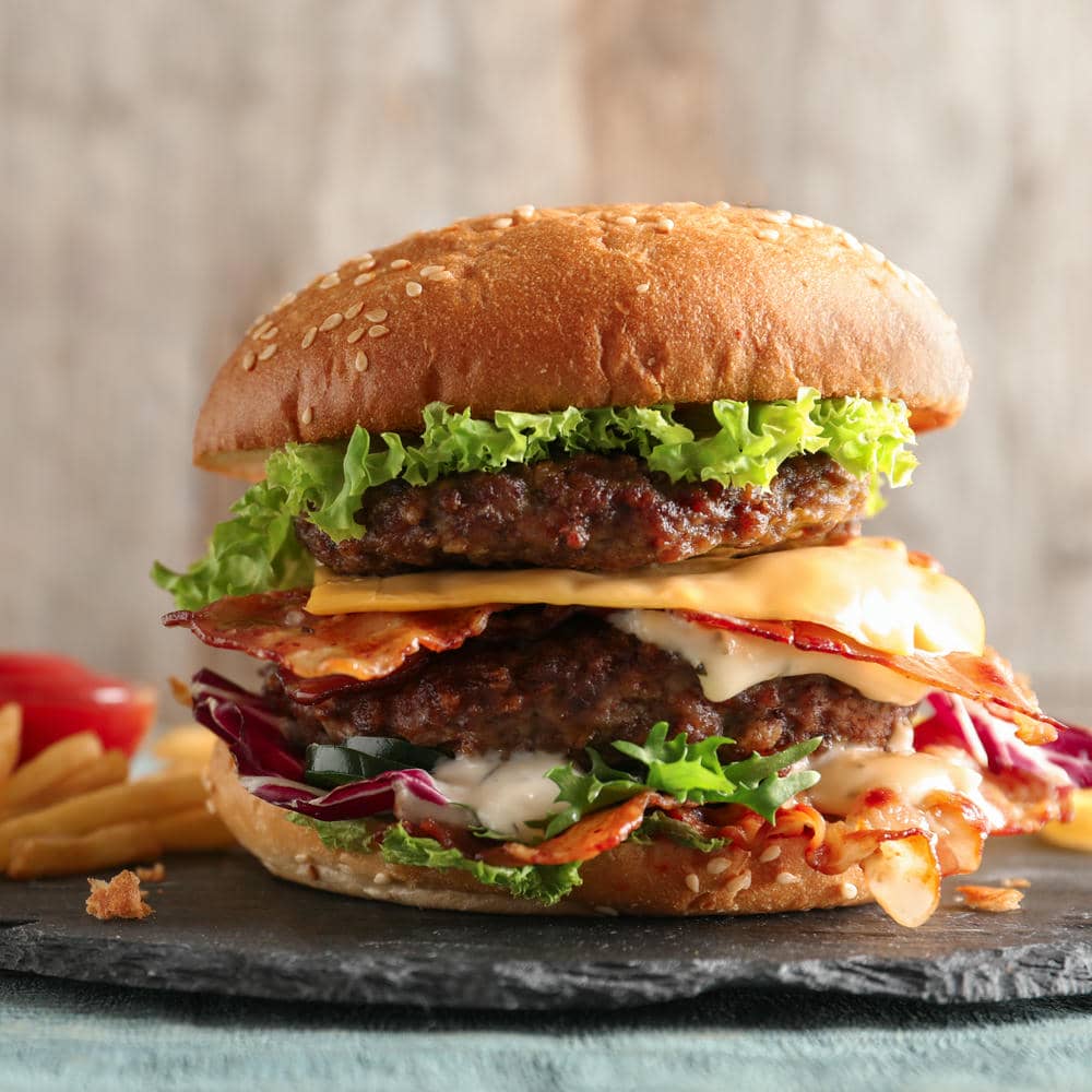 Cheeseburger with lettuce, tomato, and melted cheese on a black plate