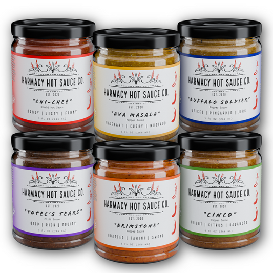 Hot sauce variety pack with six glass jars, black caps, assorted label colors