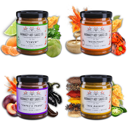Set of four hot sauce jars with black lids, featuring assorted pepper sauce labels