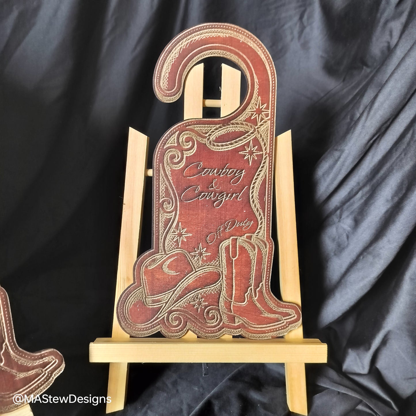 Decorative sign with cowboy and cowgirl design on a black draped background