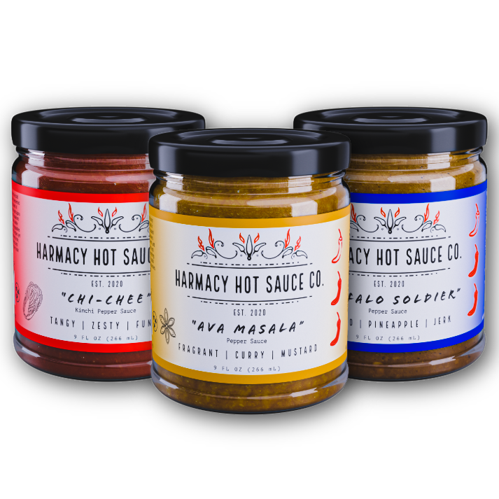 Assorted hot sauce jars with black lids, red and yellow labels in front.