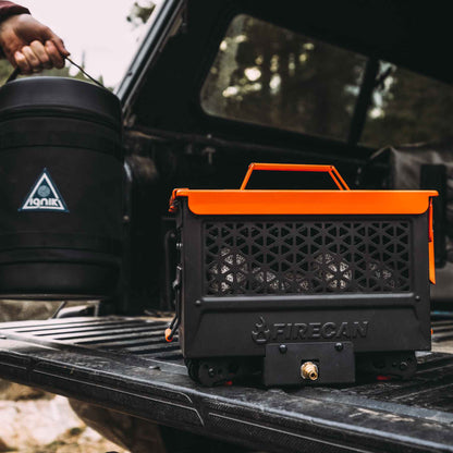 FireCan portable fire pit on truck bed, black vented front with orange handle