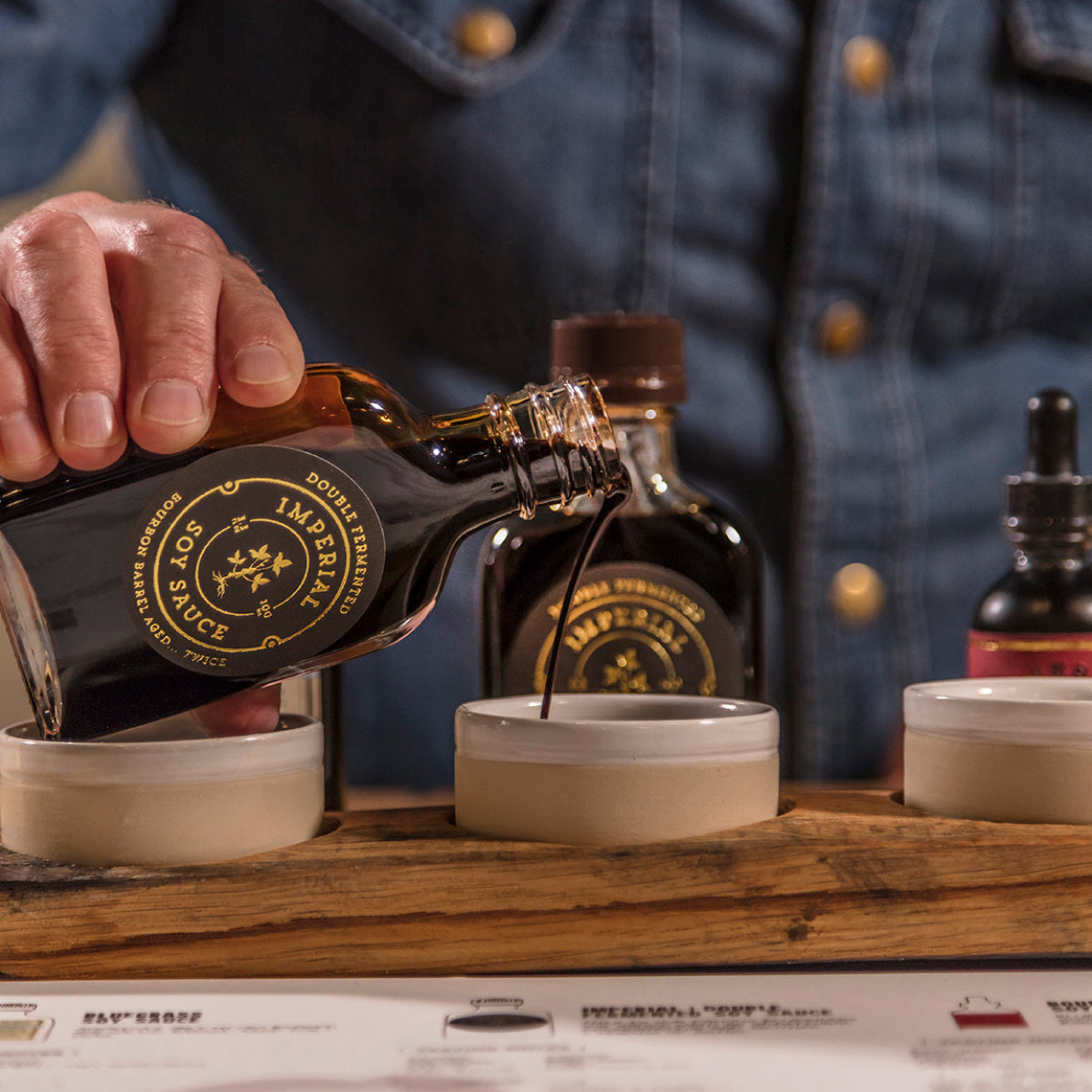 Soy sauce bottle pouring dark sauce into small bowls