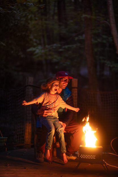 Campfire grill station with metal fire basket and visible open flames outdoors