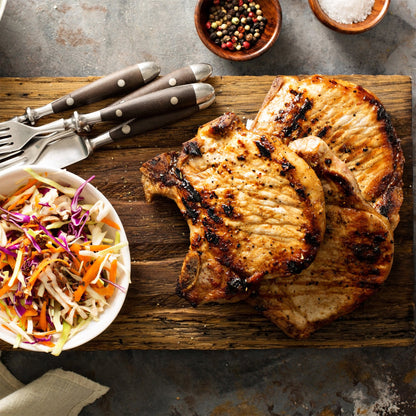 Spice-rubbed pork slices on a wooden board with shredded slaw