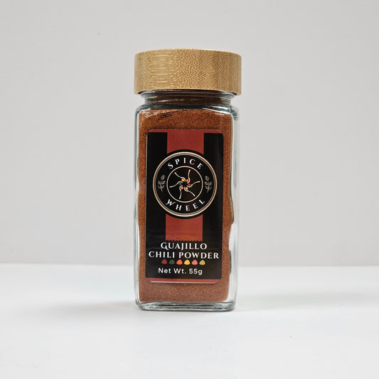 Guajillo chili powder in glass jar with gold lid, brown powder inside