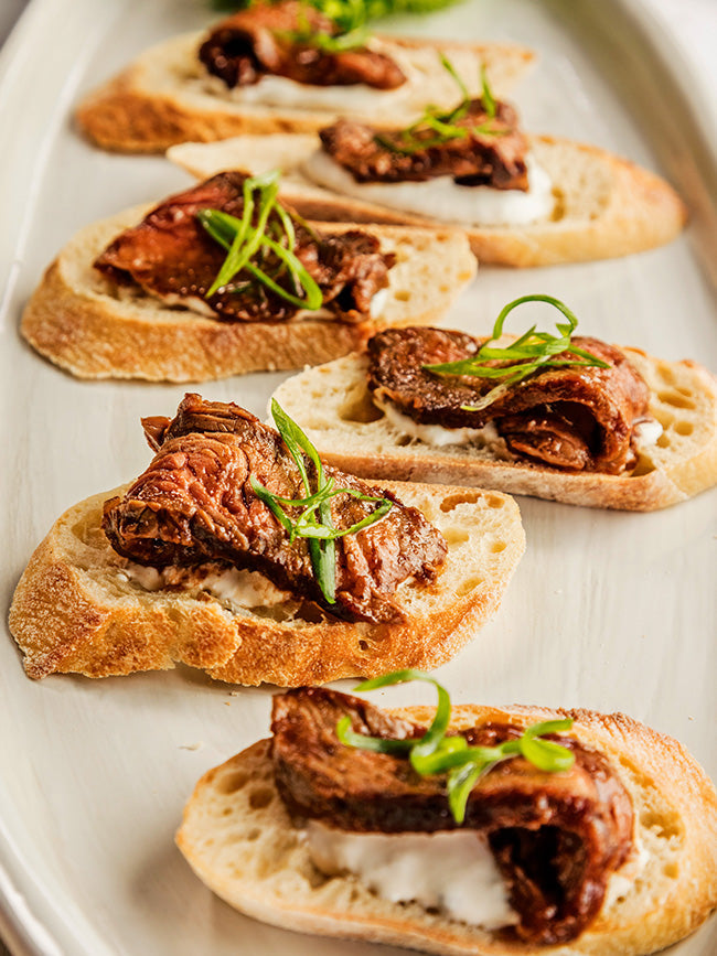 Bruschetta-style breads topped with dark sauce and sliced green onions