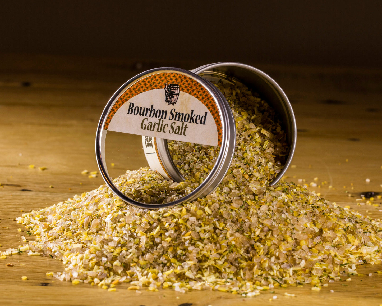 Open smoked garlic salt jar with loose seasoning crystals spread on a wooden surface