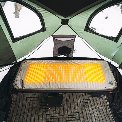 Heated fleece bed cover with glowing heating lines laid over a cot in an outdoor tent