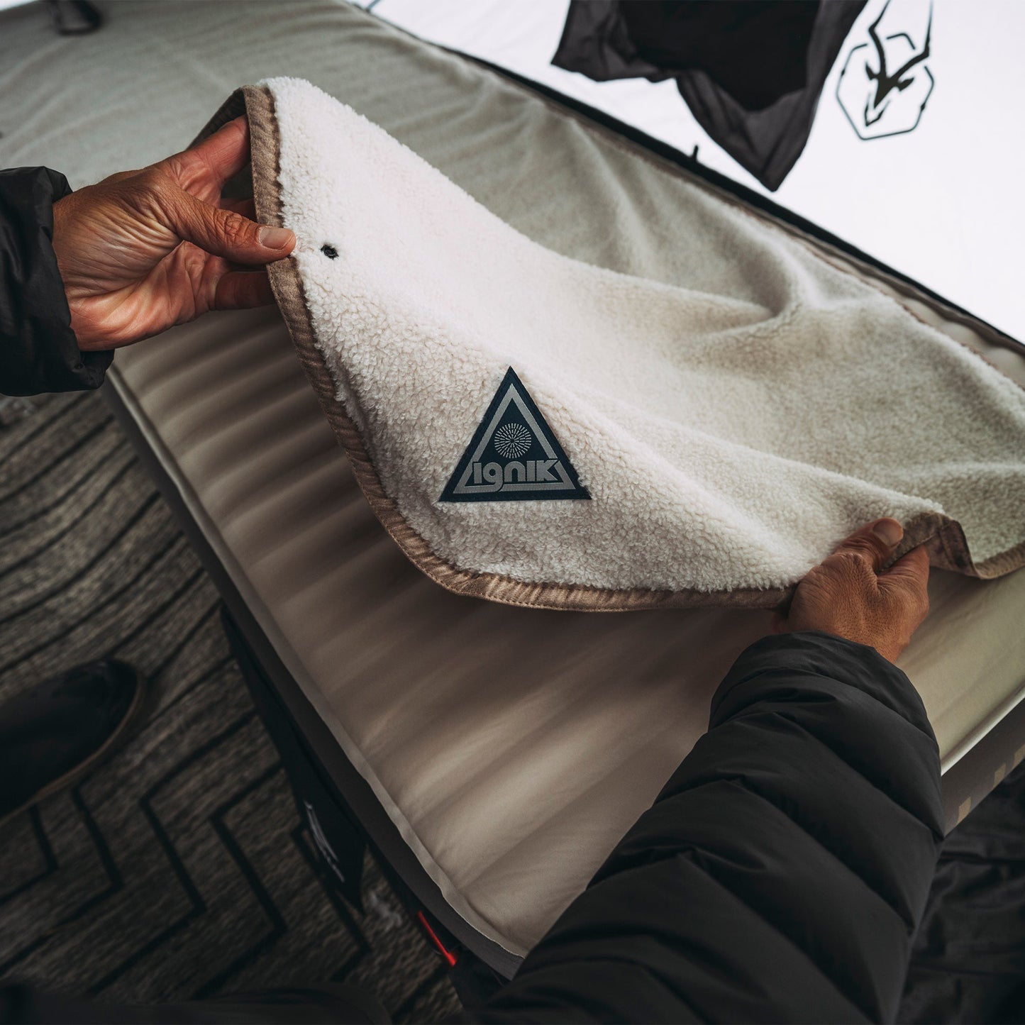 Heated fleece bed cover with triangular logo patch and textured sherpa fabric