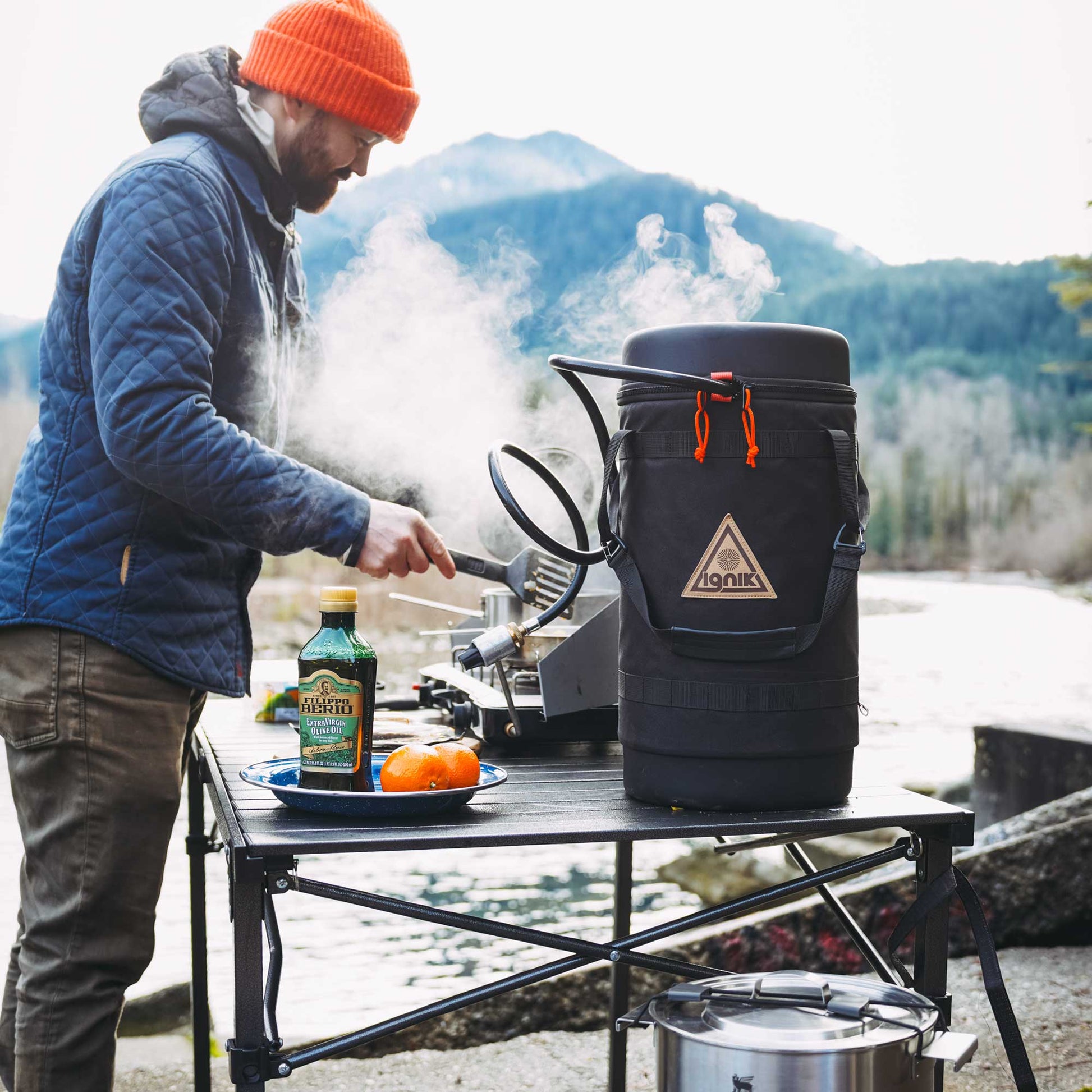 Black insulated growler bag holding a gas canister on an outdoor cooking table.