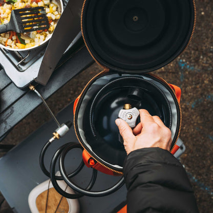 Black gas canister with cap and brass valve, opened inside an insulated bag.