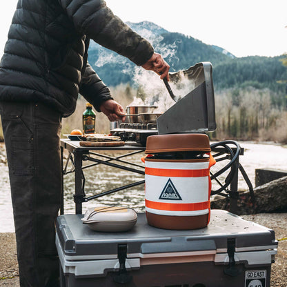 Orange-and-white insulated gas growler on an outdoor table
