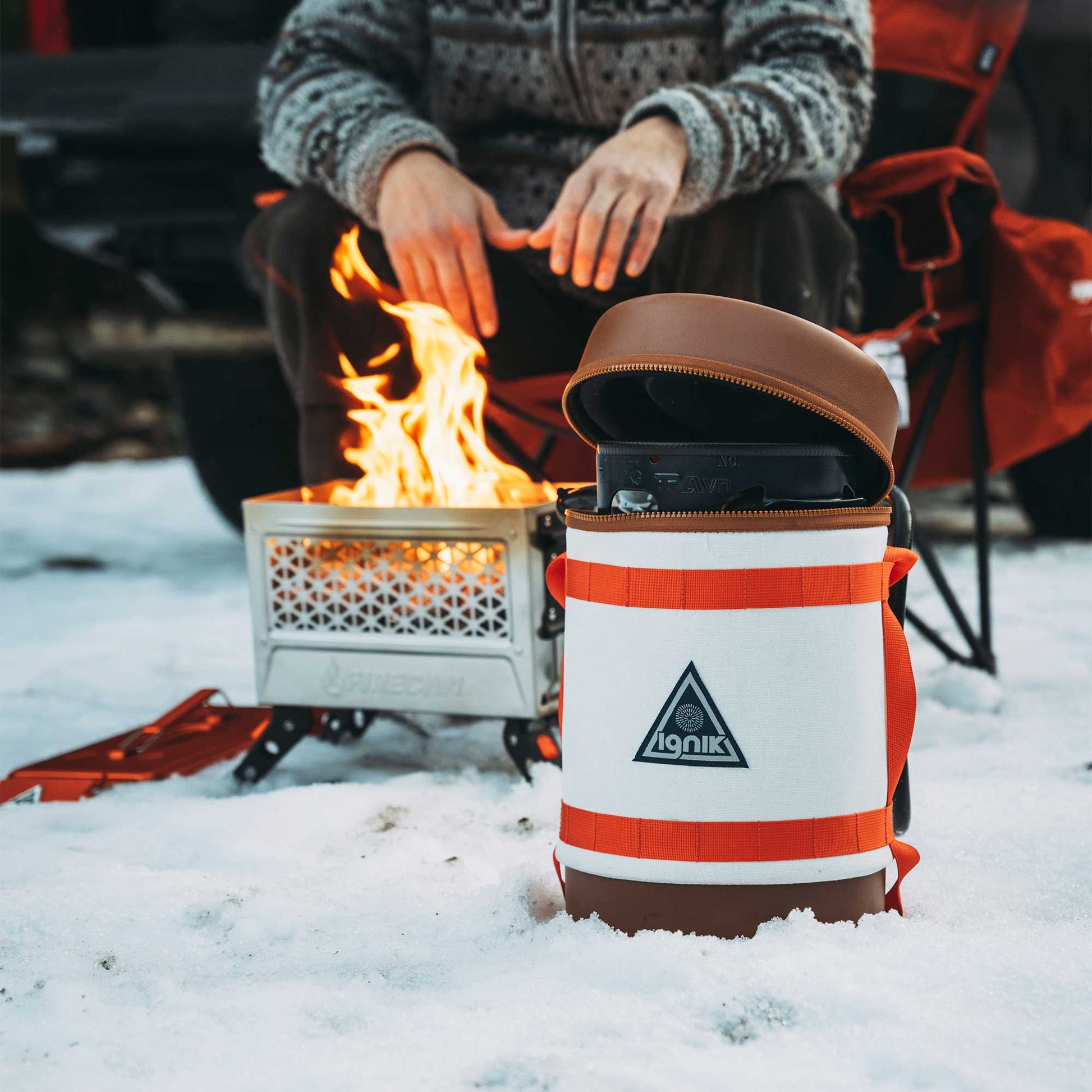 Gas growler with white-and-orange insulated case, open lid, in snowy campsite